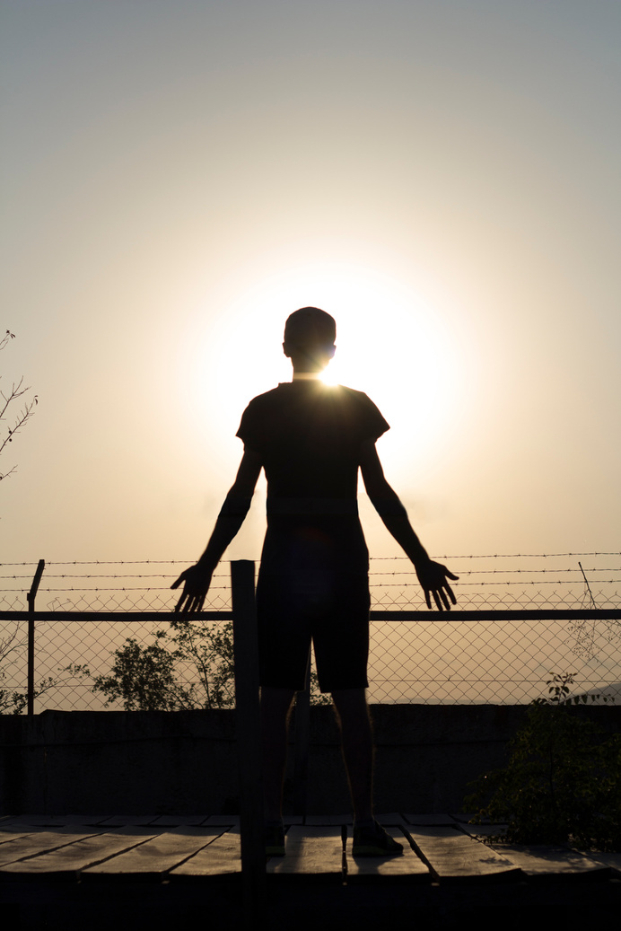 Silhouette of Man Standing Near Fence